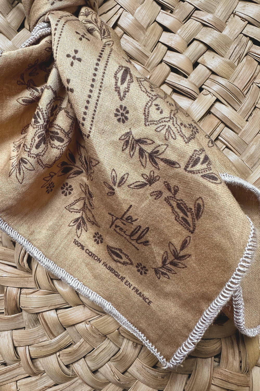 Mouchoir en coton couleur épis avec motifs floraux imprimés, finition brodée, symbolisant un savoir-faire artisanal français authentique.