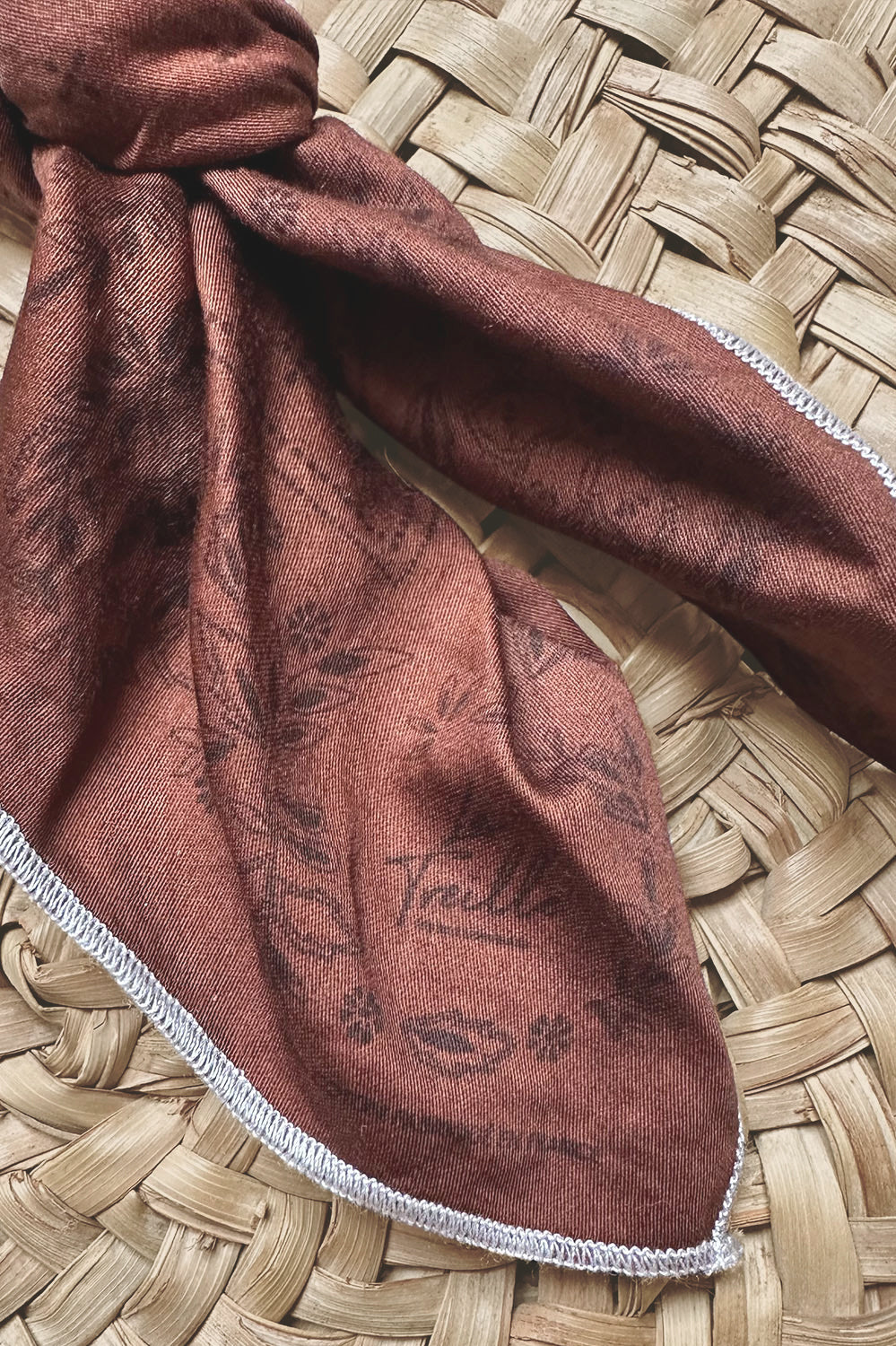 Écharpe en coton couleur rouille avec motifs floraux délicats, broderie fine et bordure cousue à la main, reflétant un savoir-faire artisanal français.