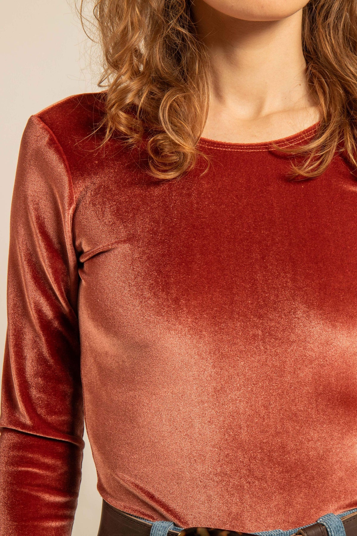 Vue rapprochée d’un body en velours ras extensible couleur terracotta avec manches longues et encolure ronde porté par une femme