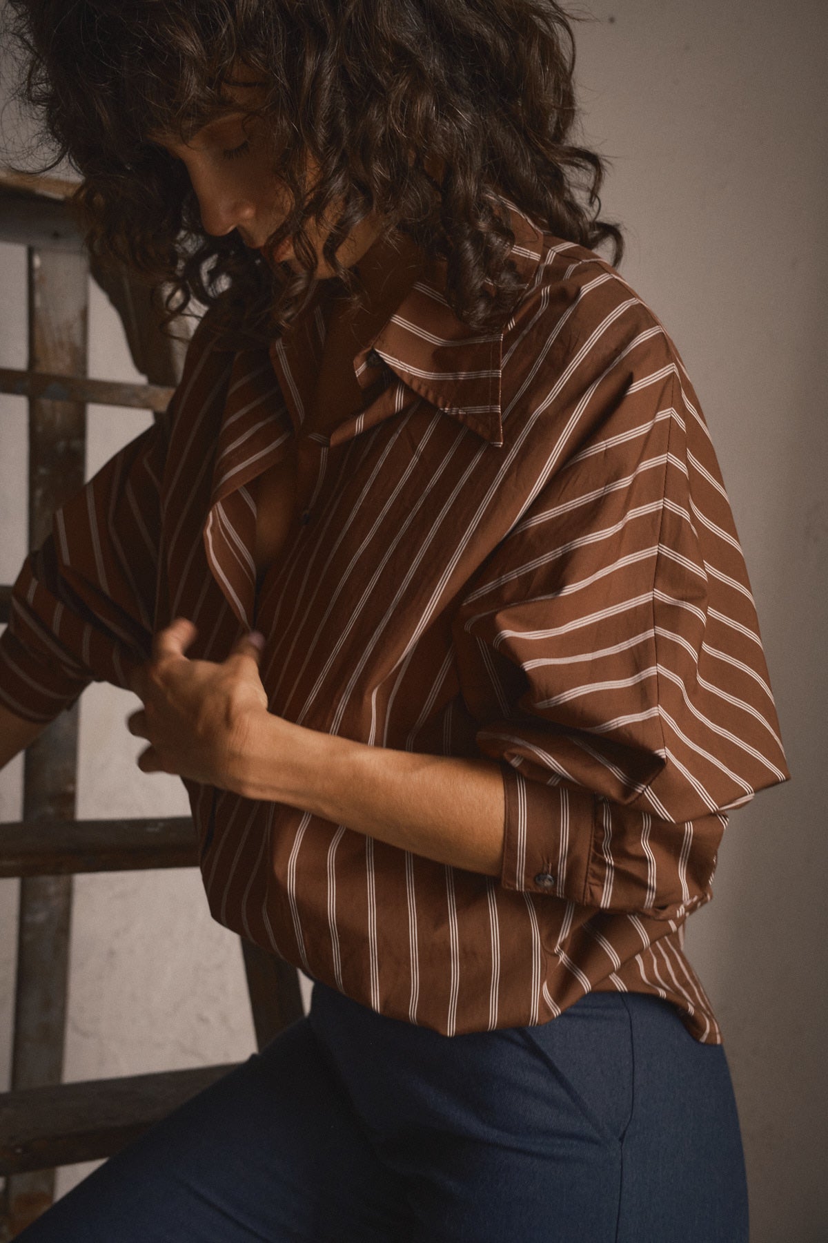 Chemise oversize chocolat à rayures portée par une femme dans un esprit années 70 avec col large et manches amples pour un look décontracté féminin