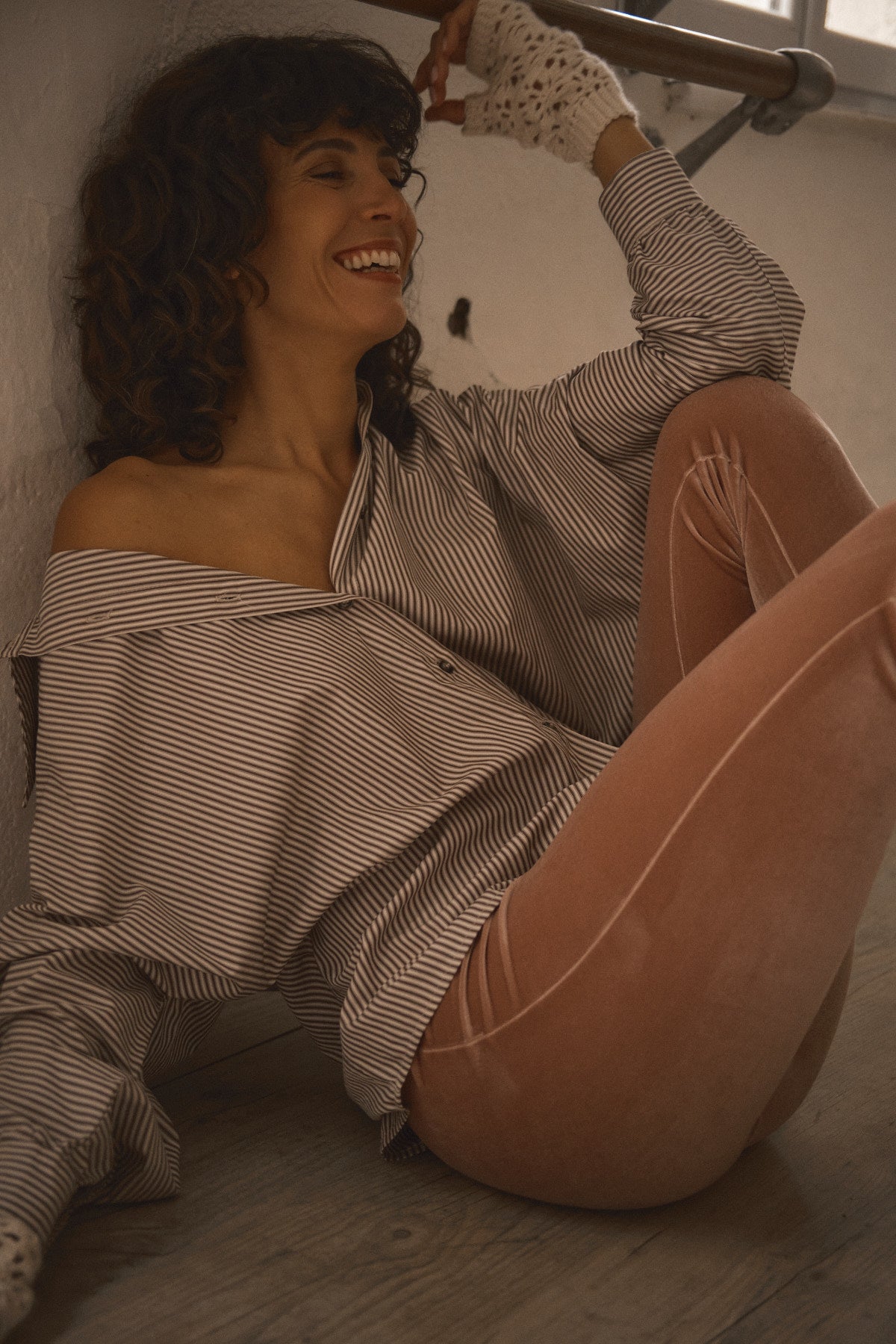 Femme portant une chemise oversize à fines rayures beige et écru avec col ouvert et manches amples dans une ambiance inspirée des années 70