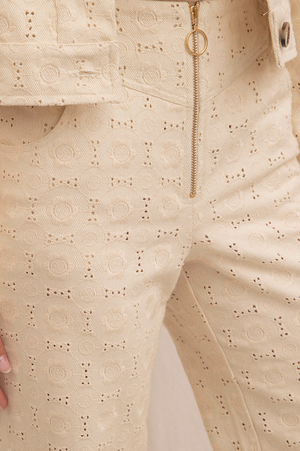 Détail du pantalon LUIGI en coton brodé écru, fermeture éclair dorée avec anneau et broderie géométrique délicate.