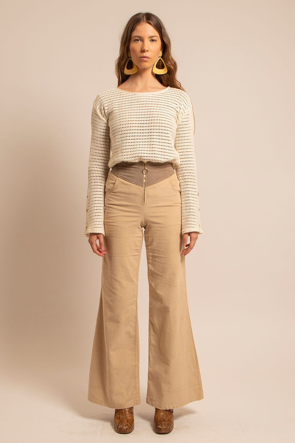 Top Holly en crochet naturel porté de face, manches longues évasées avec boutons dorés, look seventies.