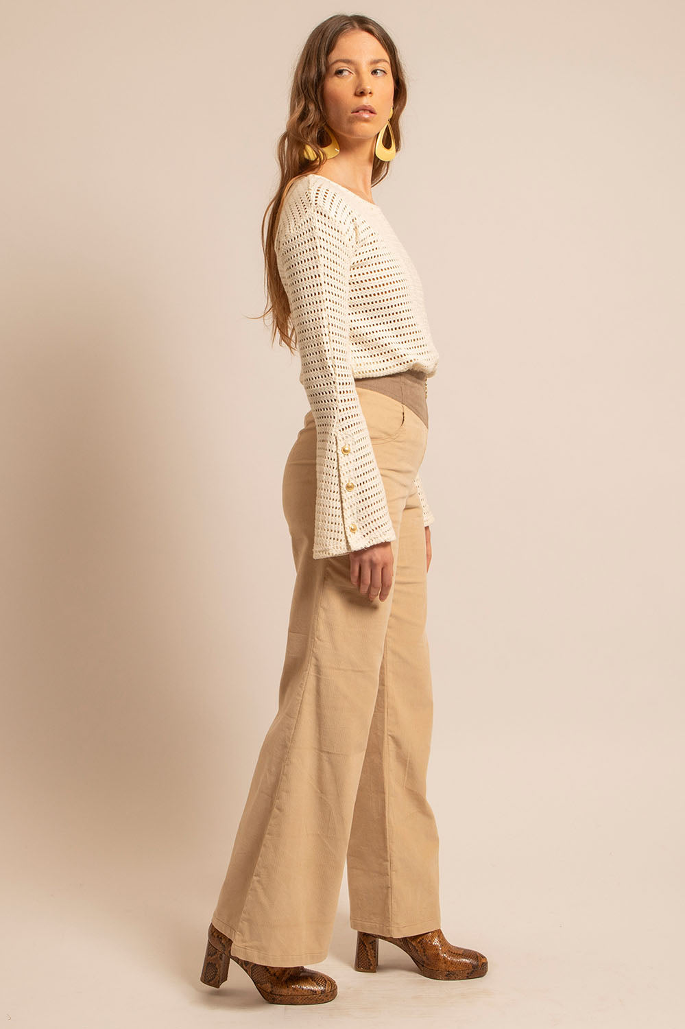 Vue de profil du Top Holly en crochet naturel, coupe droite et manches trompette boutonnées dorées.