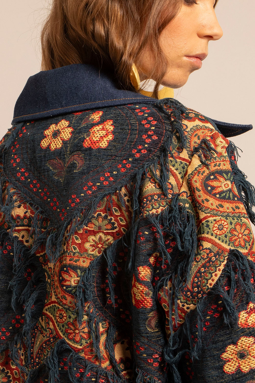 Gros plan sur le tissu jacquard fleuri et les franges de la veste Giorgia