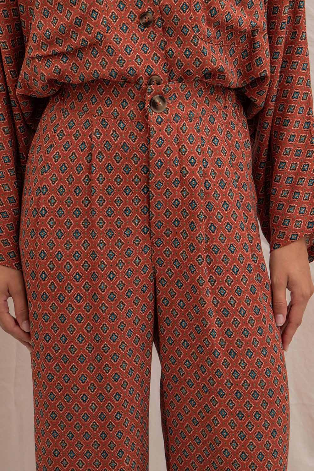 Détail du pantalon Alba femme avec braguette boutonnée et boutons marbrés, motif Terre du Sud rouge foncé.