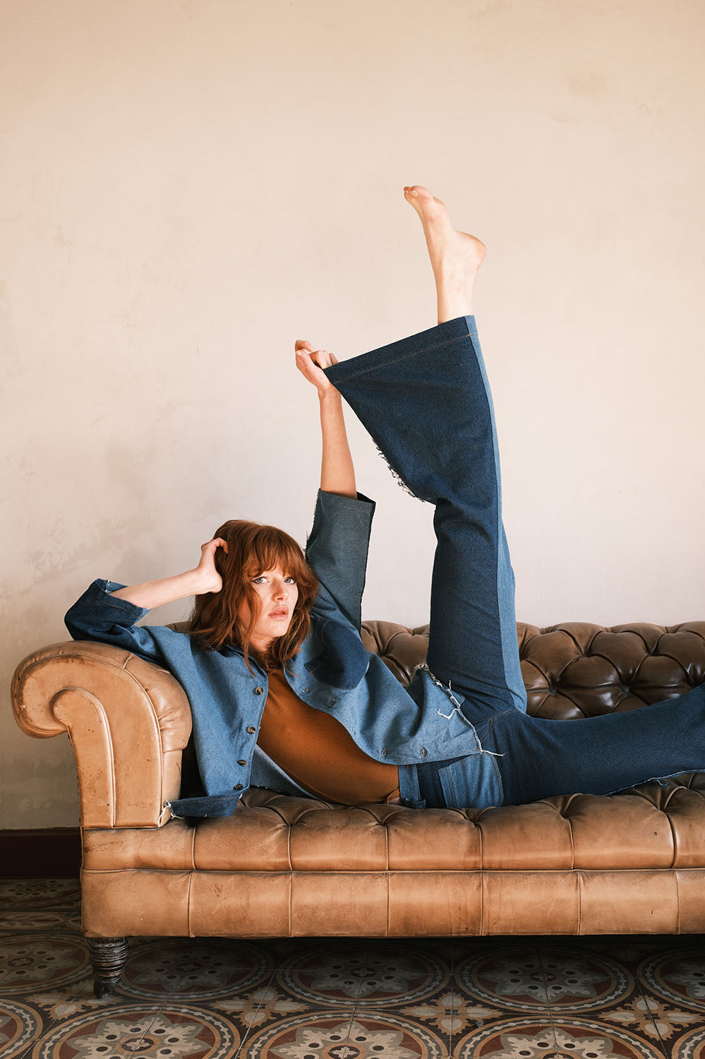 Femme allongée sur un canapé en cuir, vêtue du pantalon Farrah flare en denim bicolore La Treille