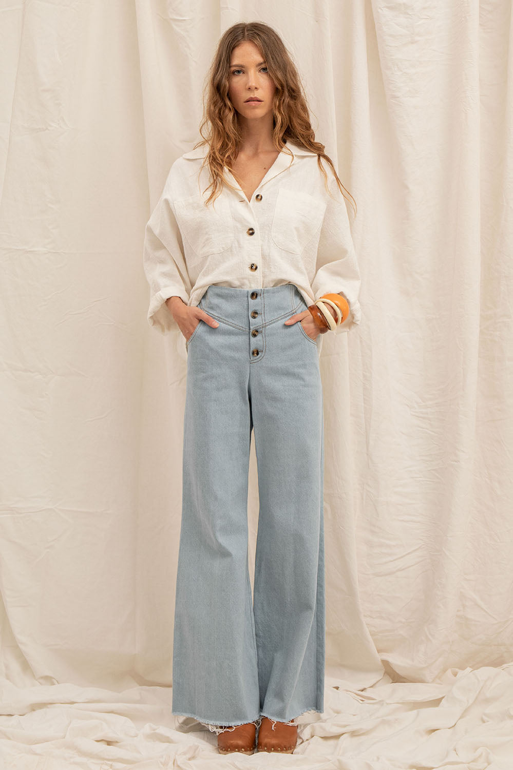 Femme portant le pantalon Maria en denim bleu délavé, coupe flare et taille haute – La Treille maison ensoleillée