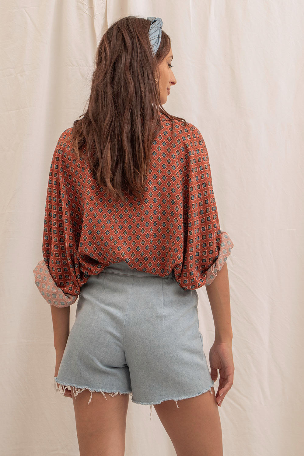 Vue de dos du short Sylvia en denim bleu délavé, coupe courte avec ceinture élastiquée et finitions brutes.