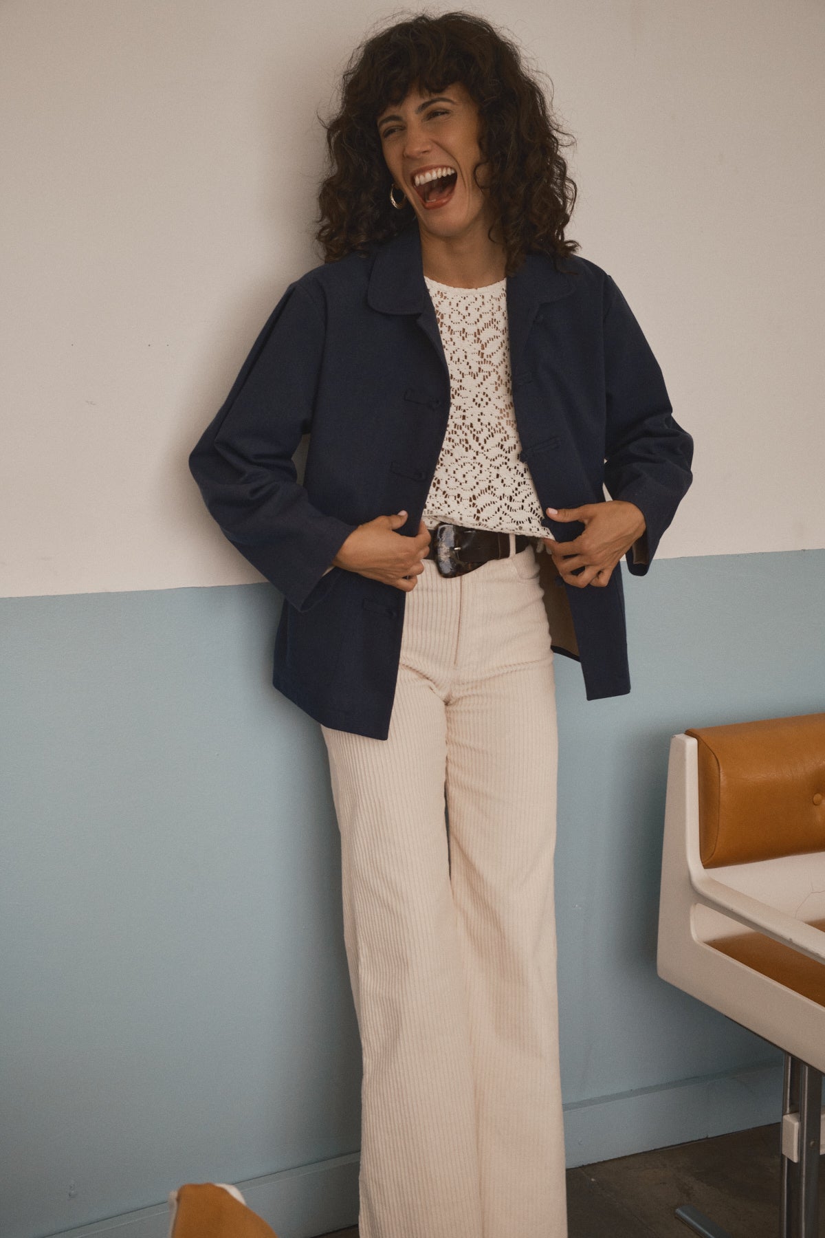 Femme portant un pantalon crème en velours côtelé à taille haute et jambe large avec une veste bleu marine dans un esprit années 70