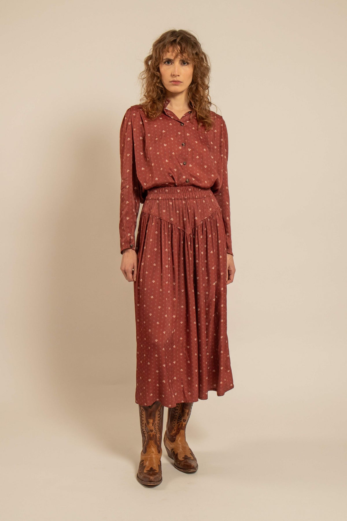 Jupe longue cerise à motifs délicats et taille élastiquée portée avec une blouse assortie et des bottes brunes pour un look féminin d’inspiration provençale.
