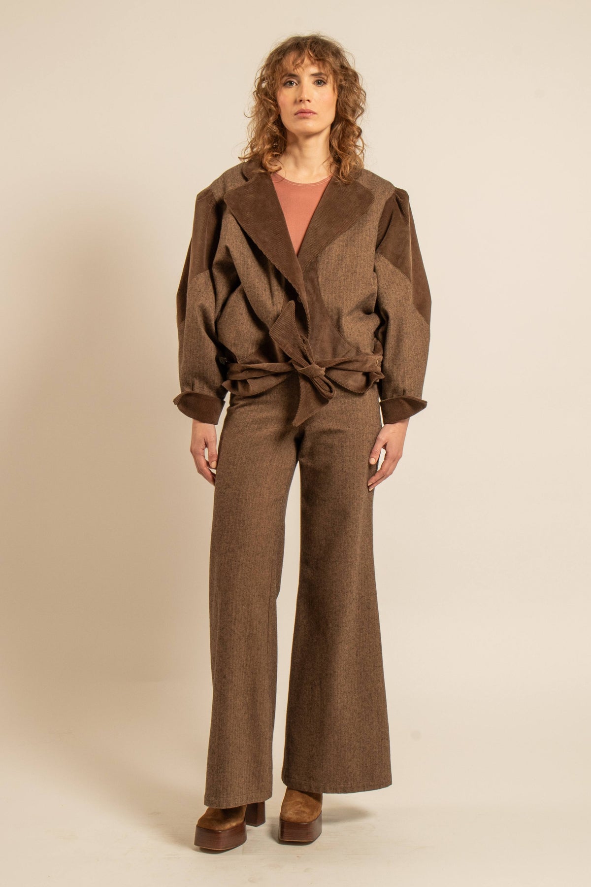 Modèle portant une veste marron oversize à ceinture nouée avec un pantalon large pour un look automne hiver élégant et décontracté