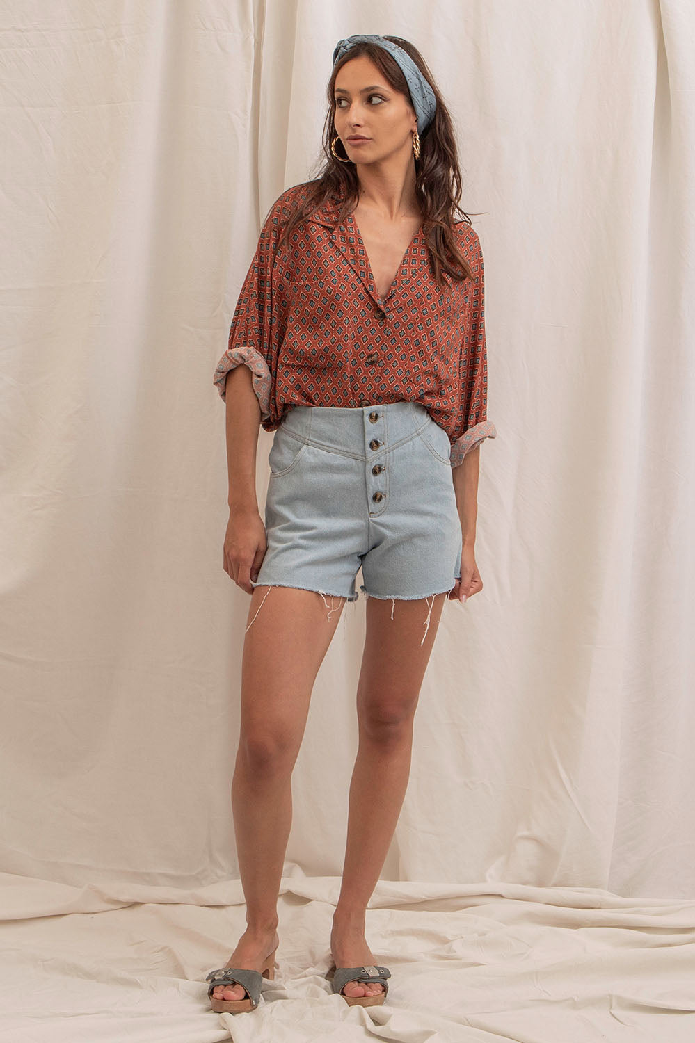 Vue de face du short Sylvia en denim bleu délavé, coupe taille haute avec boutons marbrés et bords francs.