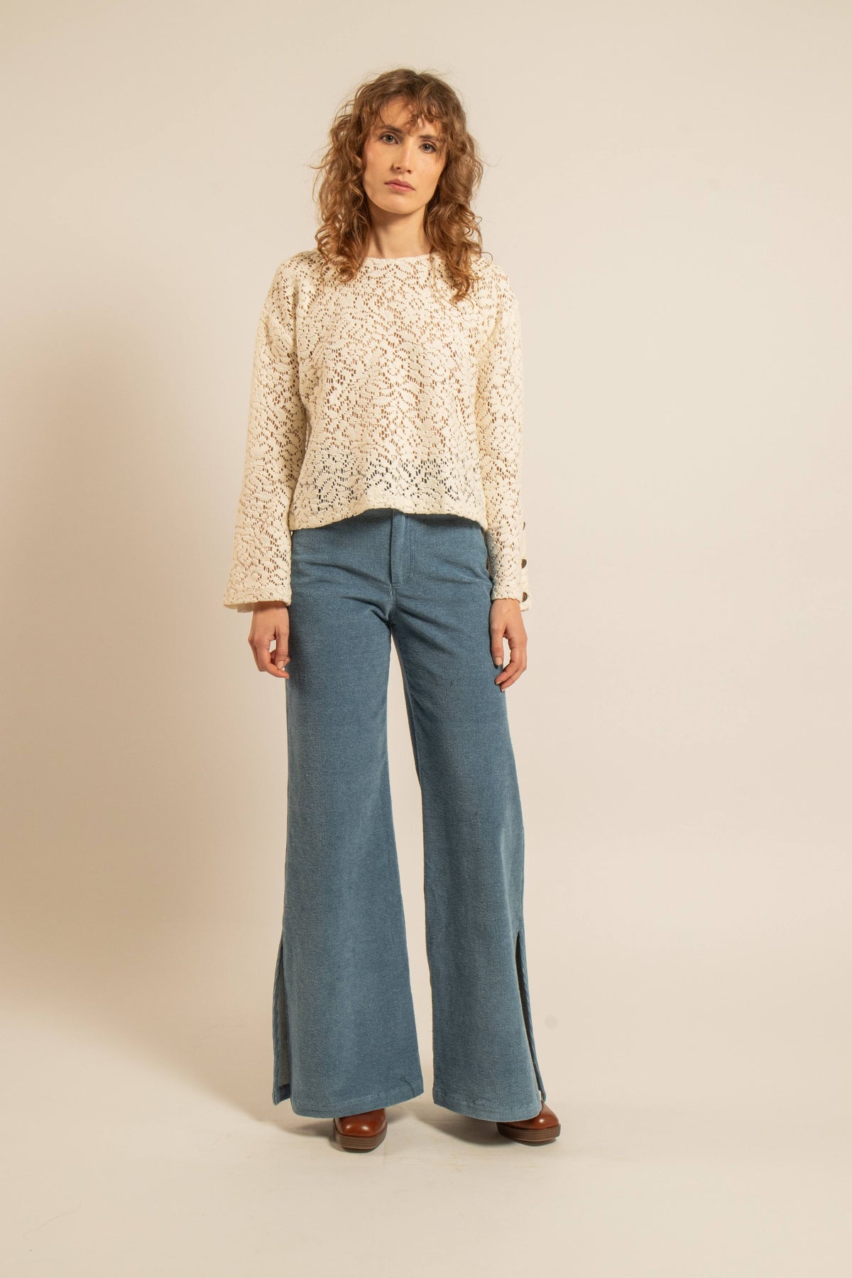 Top écru en maille ajourée esprit crochet à manches évasées porté avec un pantalon bleu à jambes larges sur un modèle féminin
