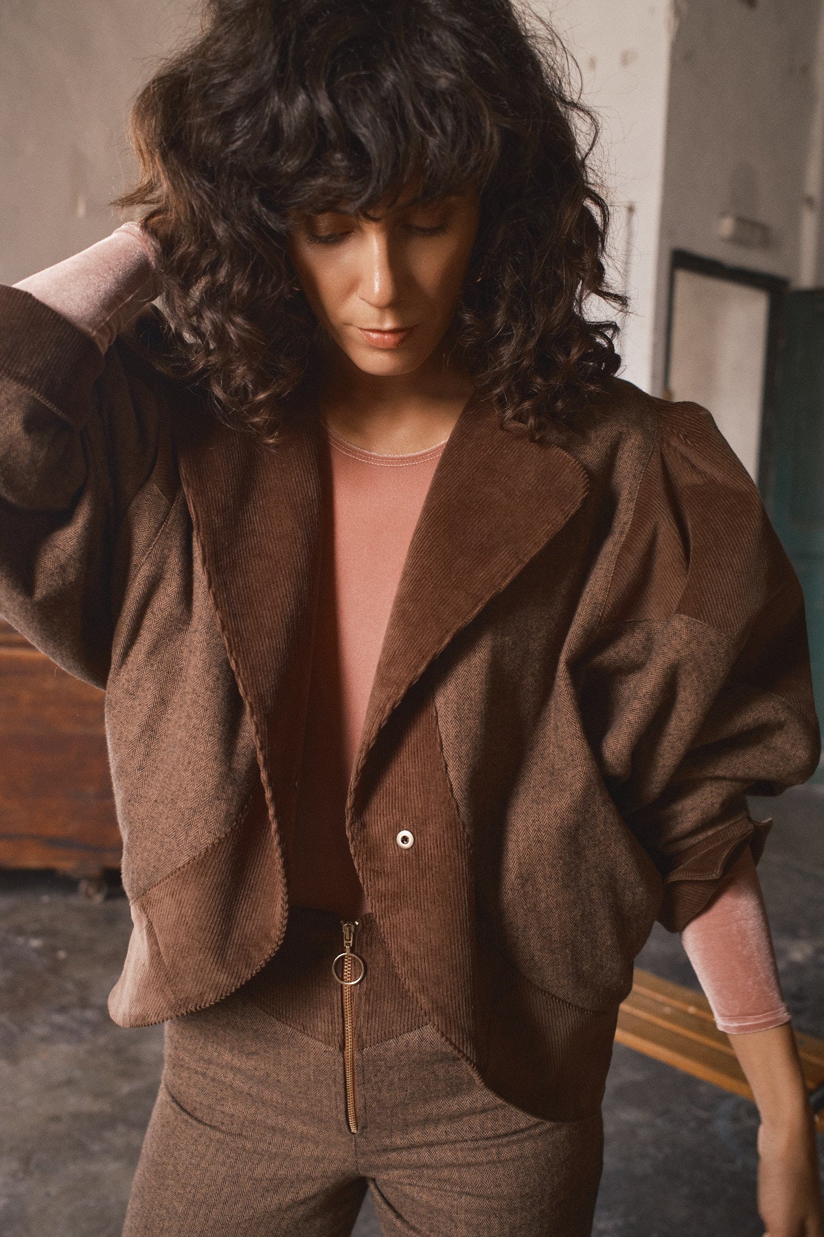 Femme portant une veste marron oversize bi-matière sur un haut rose avec pantalon assorti pour une silhouette décontractée automnale